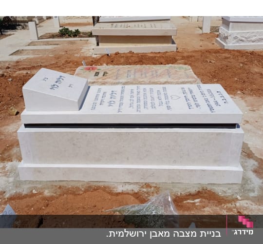 מצבה מעוצבת משיש ואבן בהירה עם כיתוב חרוט בבית עלמין